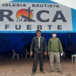 Alcides Peña and another man stand in front of the temporary church tent